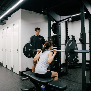 A coach watching a barbell squat at STR Fitness Club